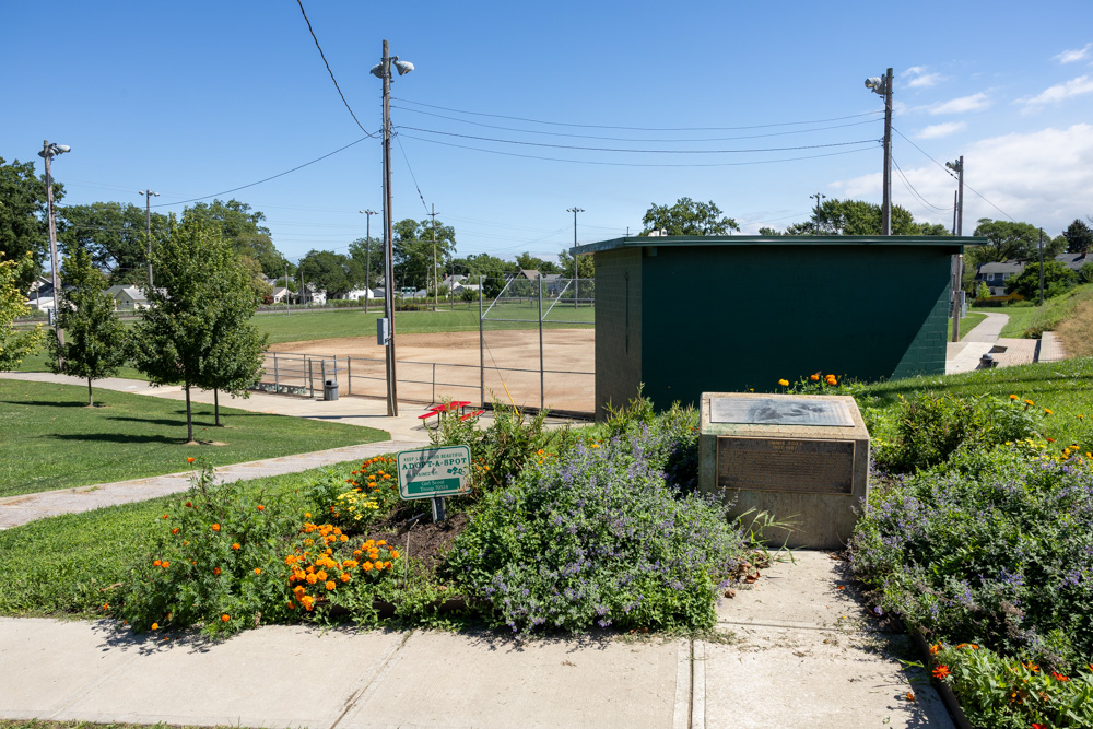 Foreground shows a flower garden and historical marker in front of Jimmie Foxx Baseball Field at Kauffman Park.