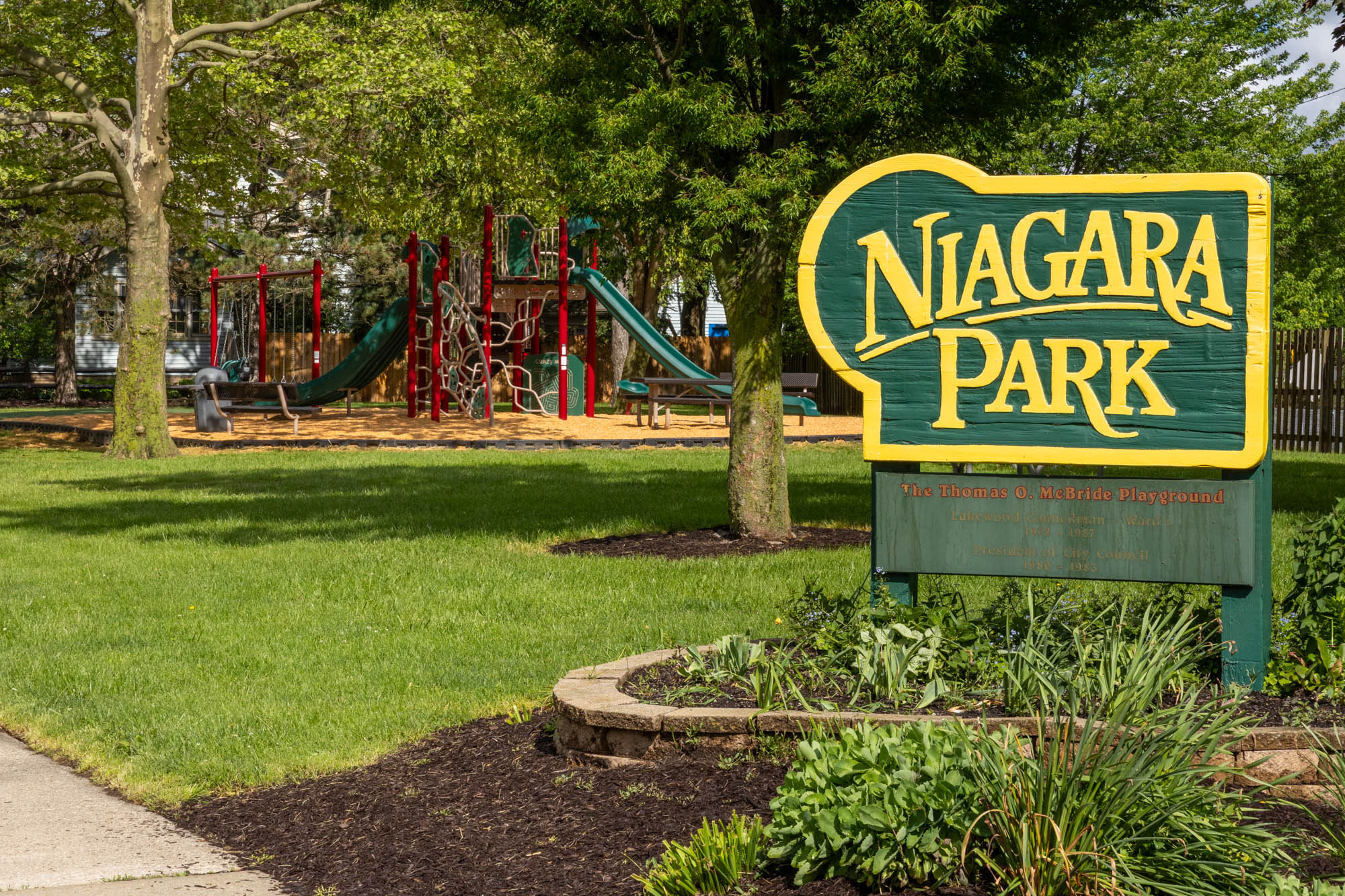 Niagara Park sign with green space and playground in background.