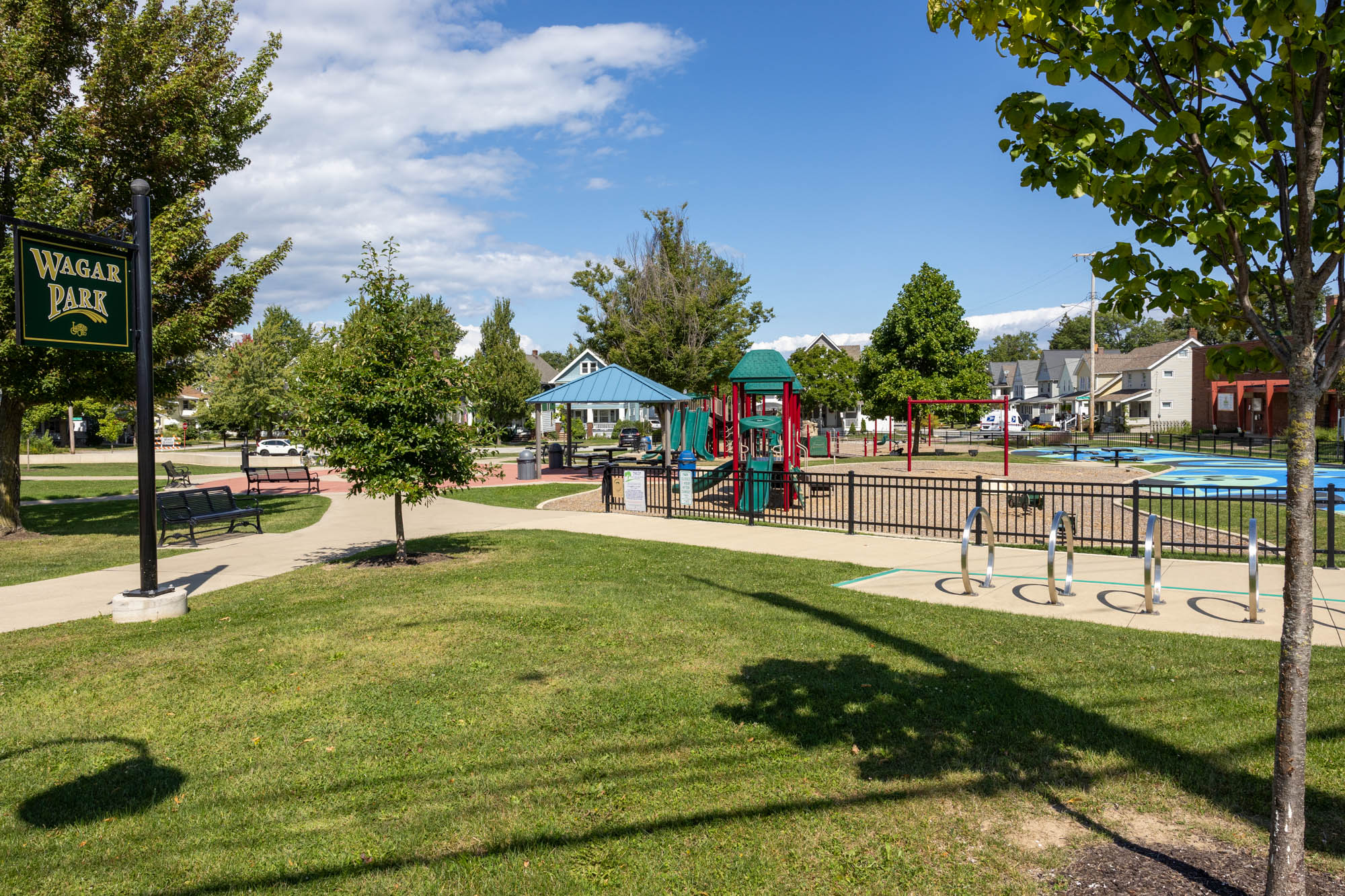 Wide view of Wagar Park including grass, trees, playground, shelter, and bike parking.