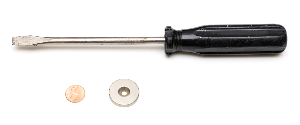 A screwdriver, a penny, and a small silver-colored magnet.