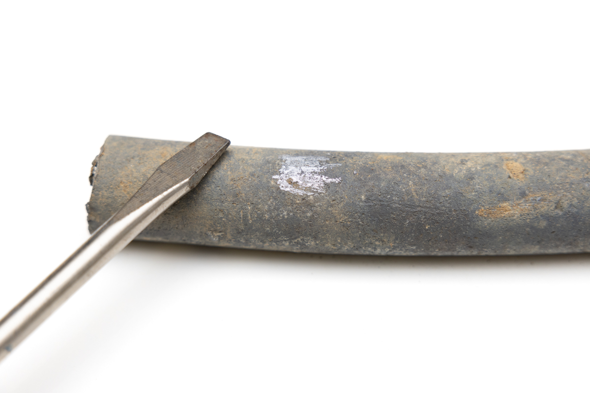 A lead pipe showing a silvery surface when scratched by a screwdriver.