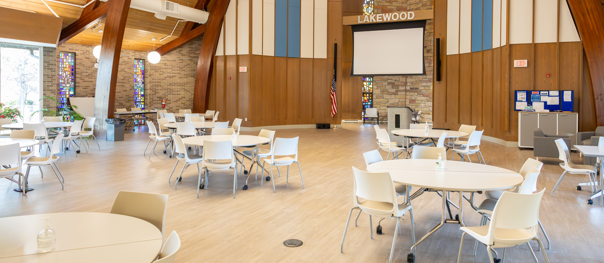 The Lawther Community Room at Cove Community Center. Large open space with several tables and chairs; cathedral ceiling.