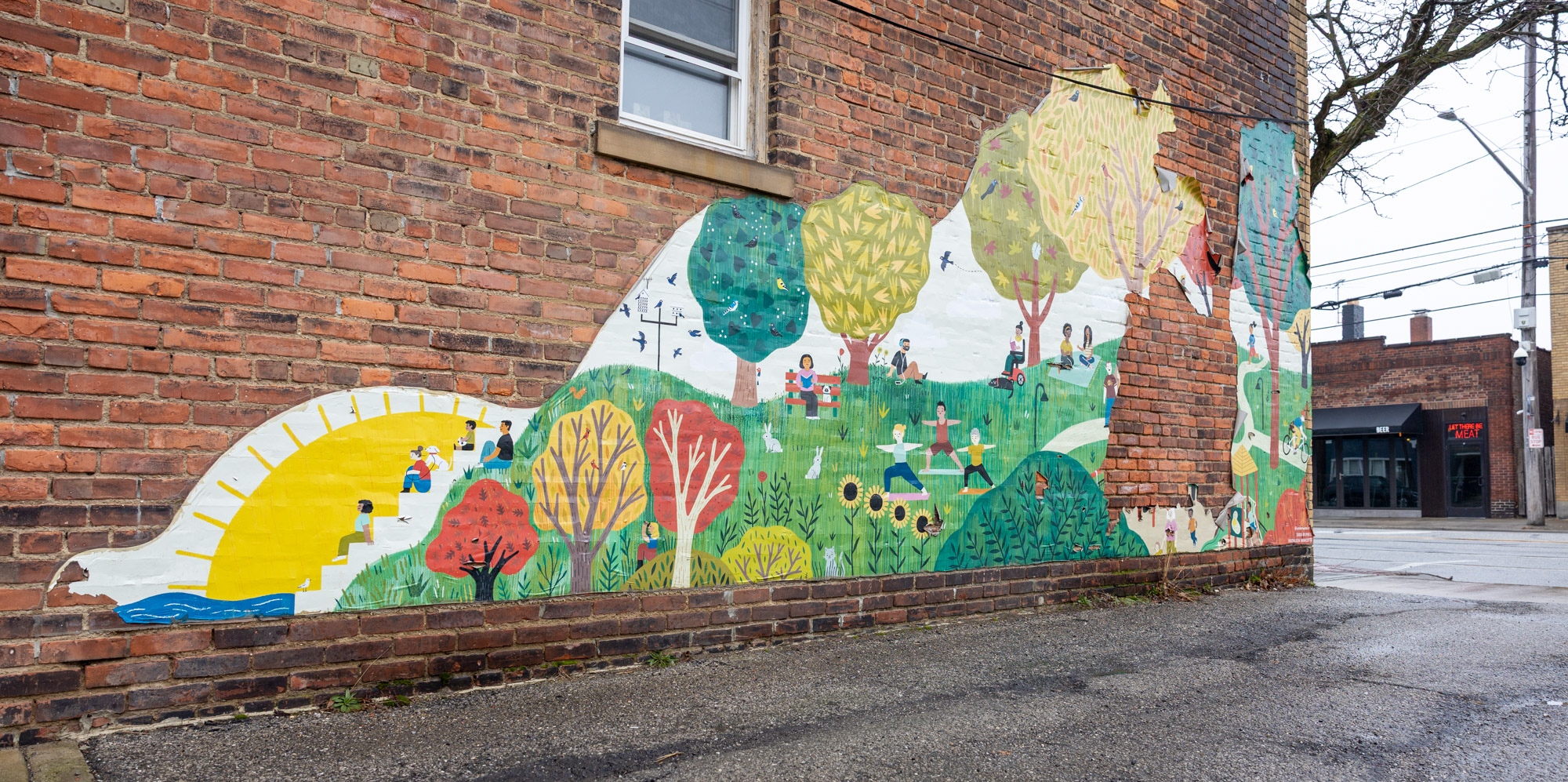 Colorful illustrated mural on a brick wall depicting people at Lakewood Park.