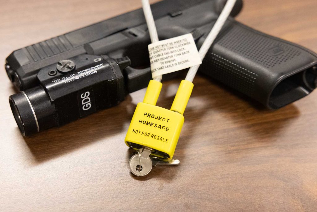 A yellow and silver gun lock and key resting on top of a black handgun.